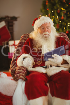 Santa holding his glasses and using tablet