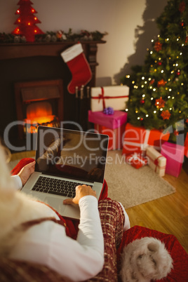 Santa sitting on the armchair and typing on laptop