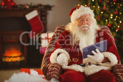 Santa holding his glasses and using tablet