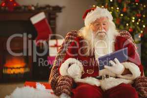 Santa holding his glasses and using tablet