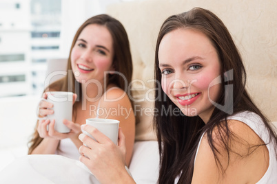 Pretty friends having coffee in bed
