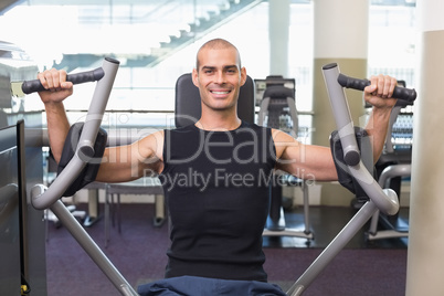 Smiling man working on fitness machine at gym