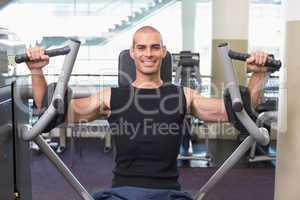 Smiling man working on fitness machine at gym