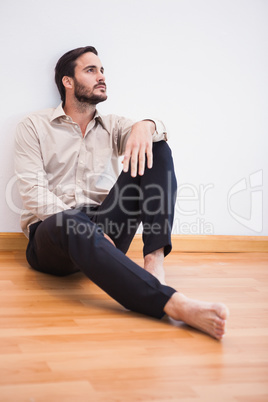 Casual thoughtful man leaning against wall looking up