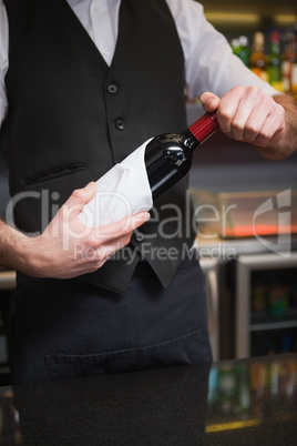 Handsome waiter opening a bottle of red wine