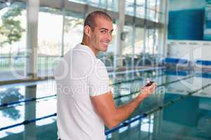 Swimming coach with stopwatch by pool at leisure center
