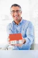 Happy man with glasses showing model house