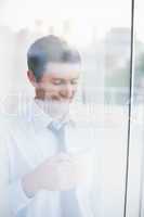 Smiling businessman holding mug seen through window