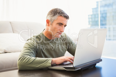 Concentrated man with grey hair using laptop