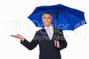 Happy businessman under umbrella with hand out