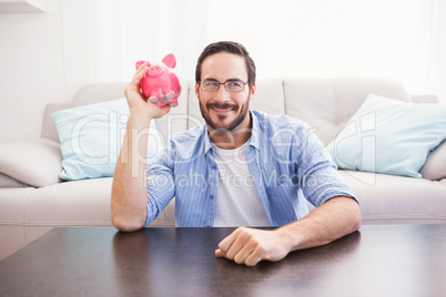 Happy man shaking a pink piggy bank