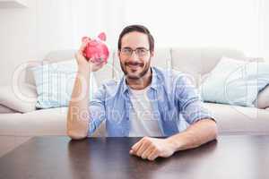 Happy man shaking a pink piggy bank