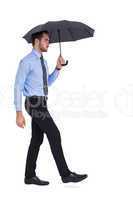 Focused businessman under umbrella stepping