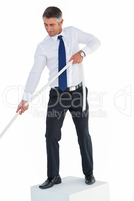 Businessman standing on cube pulling rope