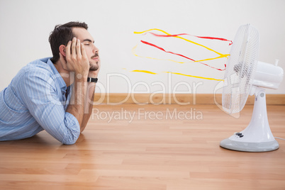 Casual man lying in front of fan