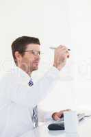 Businessman holding pen up at desk