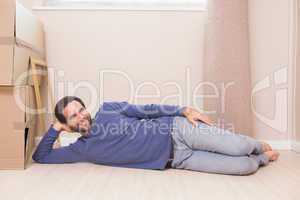 Happy man lying on floor with moving boxes