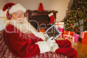 Santa claus listening music and using tablet