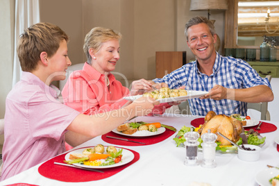 Father holding dish while grandmother serving herself
