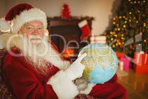 Smiling santa pointing his finger on the globe