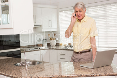 Senior man using his laptop on the phone