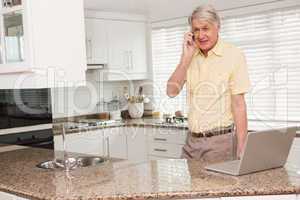 Senior man using his laptop on the phone