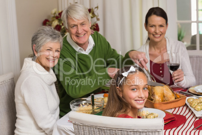 Smiling grandfather carving chicken during christmas dinner