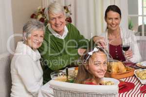 Smiling grandfather carving chicken during christmas dinner