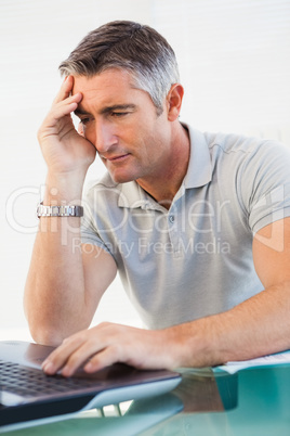 Tired man sitting and using his laptop