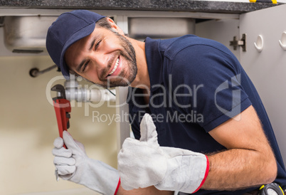 Plumber smiling at the camera fixing under the sink