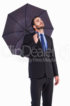 Businesswoman in suit holding umbrella while looking up