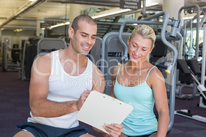 Woman discussing her performance on clipboard with a trainer at