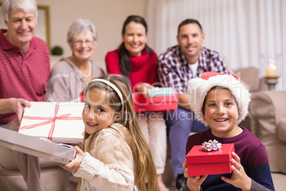 Brother and sister holding gift in front of their family