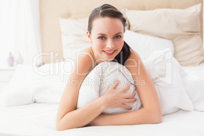 Pretty brunette smiling at camera in bed