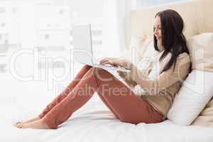 Pretty brunette using laptop on bed