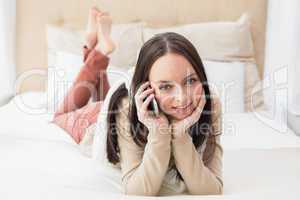 Pretty brunette making a call on bed