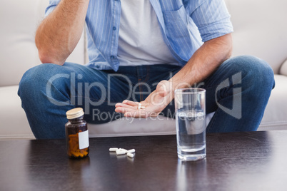 Man taking his pills on couch