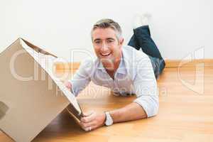 Happy man lying on floor with box looking at camera
