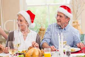Cute mature couple in santa hat at christmas dinner