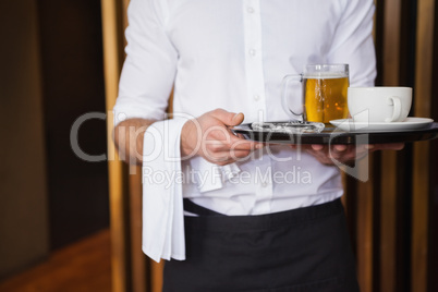 Smiling waiter holding tray with coffee cup and pint of beer