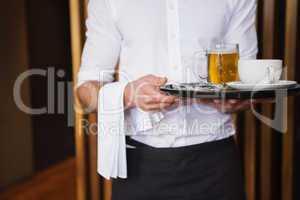 Smiling waiter holding tray with coffee cup and pint of beer