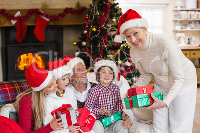 Family wearing christmas hat while holding presents