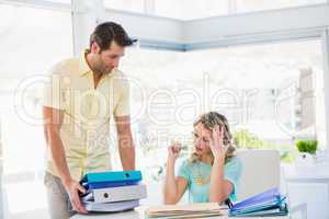 Tired creative businesswoman with stack of files on desk