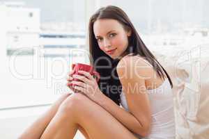Pretty brunette sitting on floor with mug