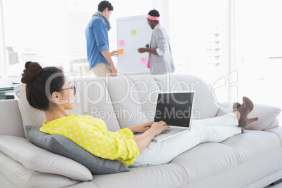 Young creative woman using laptop on couch