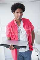 Portarit of a serious businessman holding laptop
