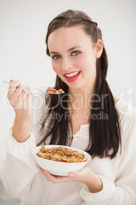 Pretty brunette eating bowl of cereal