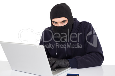 Hacker in balaclava hacking a laptop
