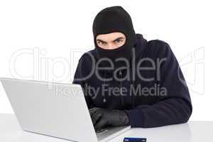 Hacker in balaclava hacking a laptop