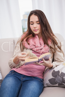 Pretty brunette reading book on couch